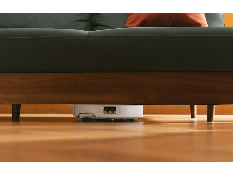 Hvid Roborock Qrevo Edge 2 Pro kører ind under en sofa med træben på et trægulv