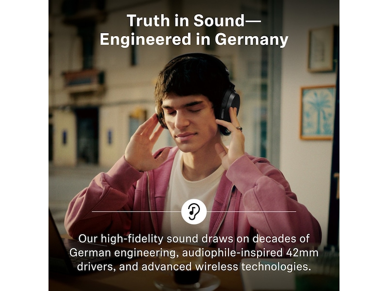 Ung mand i lyserød hættetrøje med lukkede øjne, sorte Sennheiser MOMENTUM 5 og hænderne på ørekopperne